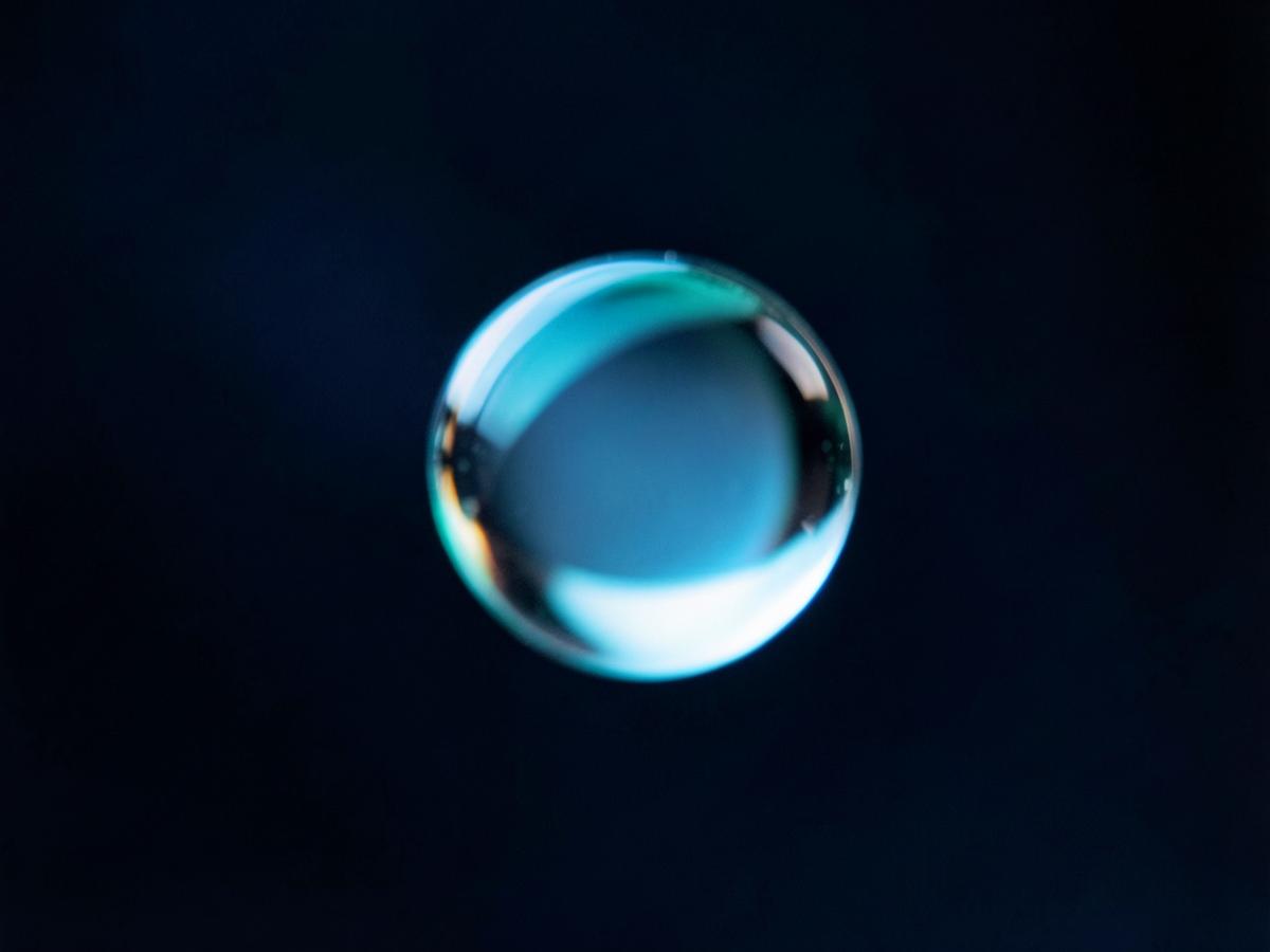 Macro photograph of a single water droplet refracting blue and aqua light